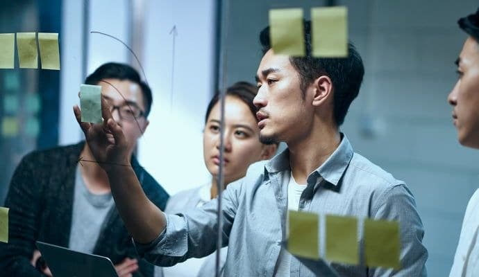 Team planning around a glass wall with sticky notes