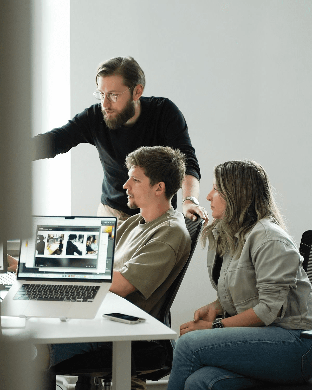 Team members collaborating around a laptop at a standing desk